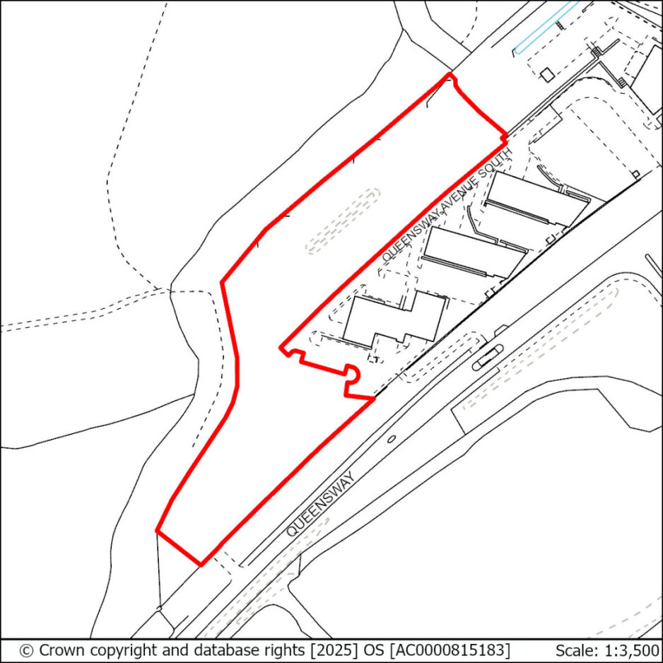 Outline of a property in red along Queensway South, adjacent to buildings and a road with a vehicle.