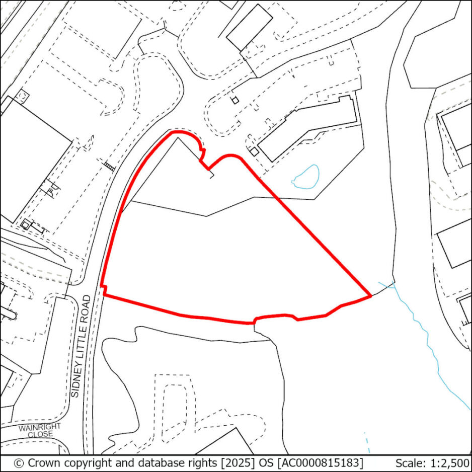 A map showing a plot of land outlined in red, with surrounding roads and buildings. The map includes a small water feature and a stream within the outlined area.