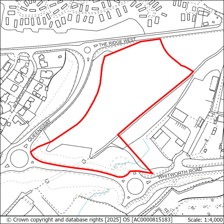 A map showing a plot of land outlined with a red border, located near roundabouts at Queen's Way and Whitworth Road, with surrounding residential and commercial buildings.
