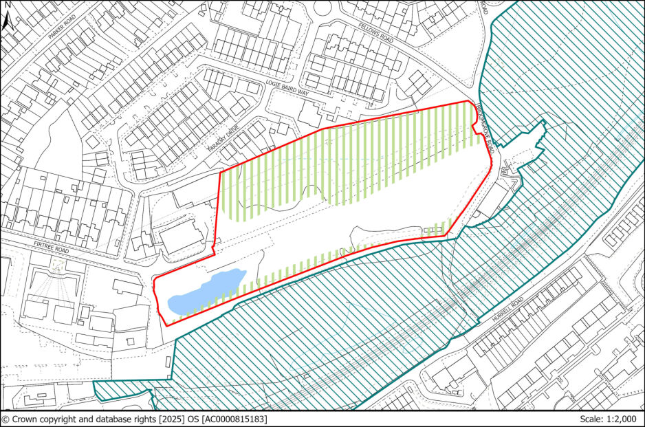 A detailed map showing a land area outlined with a red border, including a pond at the southwestern end and surrounding green and blue striped zones. The map features nearby residential streets and plots, with some areas shaded in hatched lines.